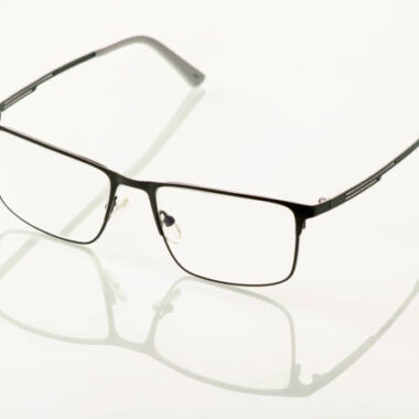 Glasses in a black metal frame are reflected in a white mirror background.